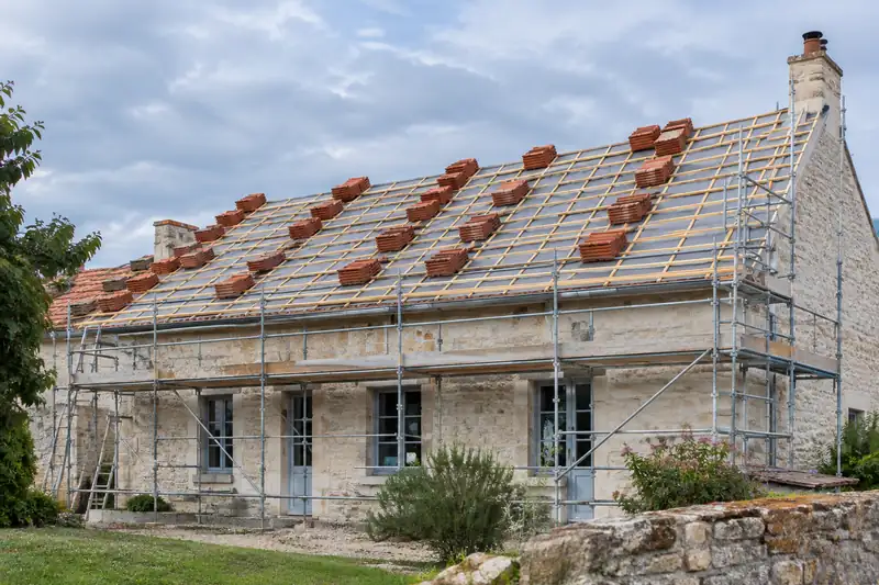Rénovation de toiture : échafaudage, liteaux, écran de sous-toiture et tuiles neuves sur une maison en pierre